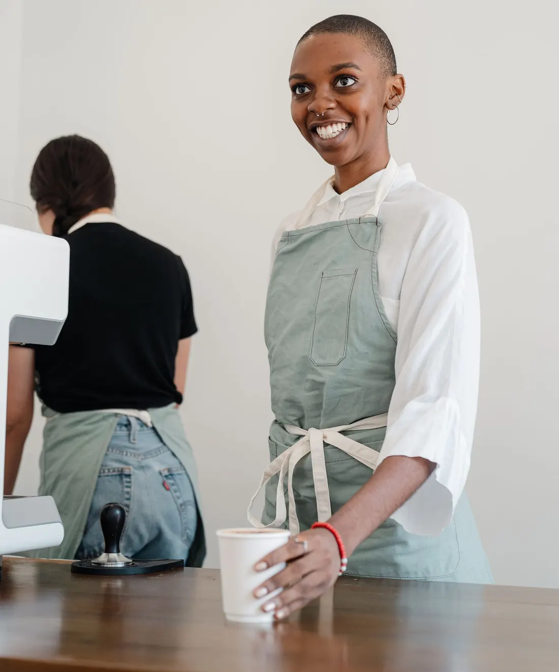 Une barista souriante tend un café à un client